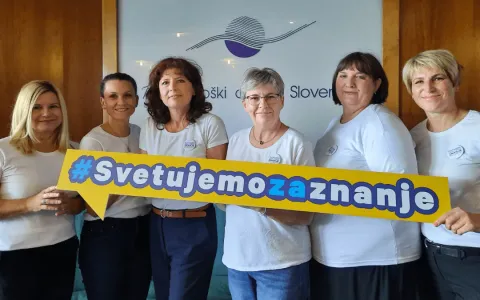 Skupina šestih žensk, oblečenih v belo, nosi broške z napisom “SVETUJEMO ZNANJE”. V rokah držijo napis: “SVETUJEMO ZA ZNANJE”